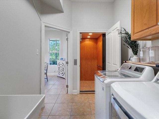 washroom featuring light tile patterned floors, cabinets, and washer and clothes dryer