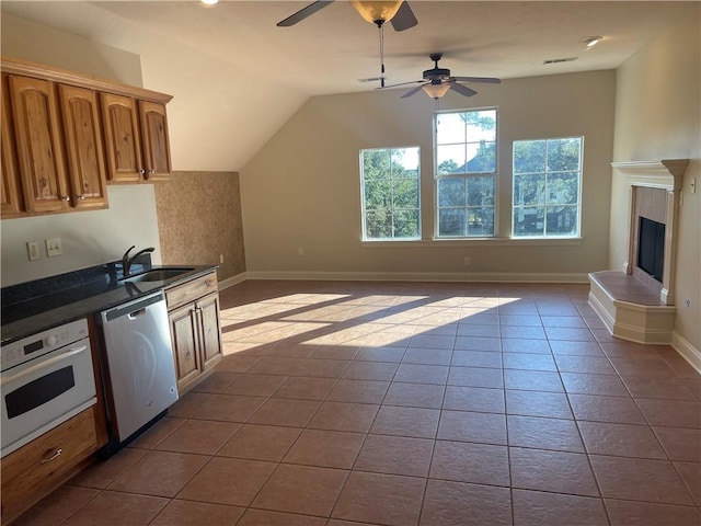 kitchen featuring white oven, sink, vaulted ceiling, ceiling fan, and stainless steel dishwasher