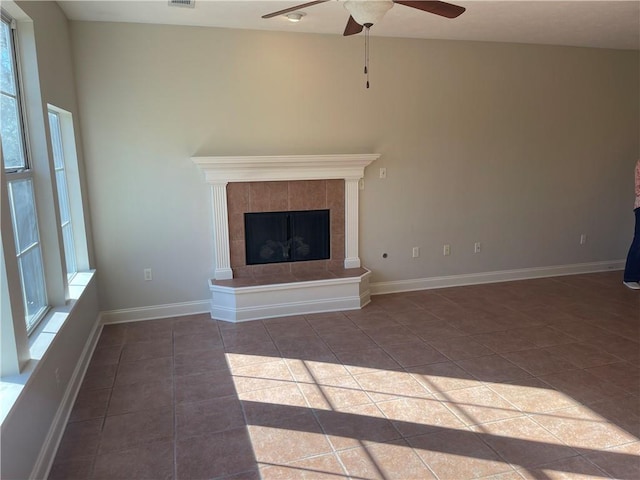 unfurnished living room featuring ceiling fan, a tiled fireplace, and tile patterned flooring