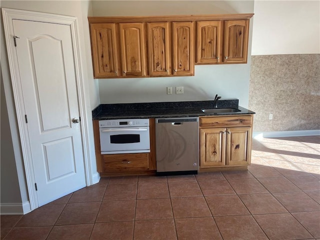 kitchen featuring sink, dark tile patterned flooring, dishwasher, and oven