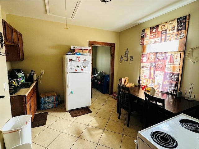 kitchen featuring light tile patterned floors, stove, and white fridge