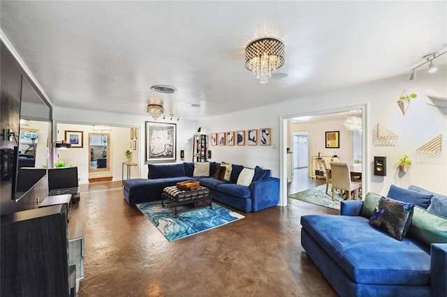 living room with a notable chandelier, concrete floors, and track lighting