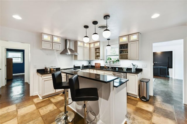 kitchen featuring wall chimney exhaust hood, a center island, and a healthy amount of sunlight