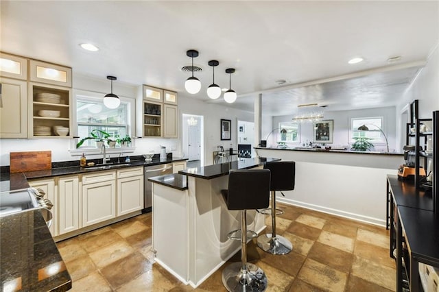 kitchen with dishwasher, sink, light tile patterned floors, a center island, and a breakfast bar