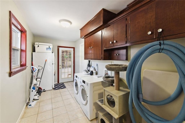 laundry area with washing machine and dryer, cabinets, and light tile patterned floors