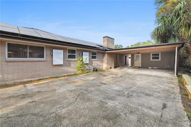 ranch-style home with a carport and solar panels