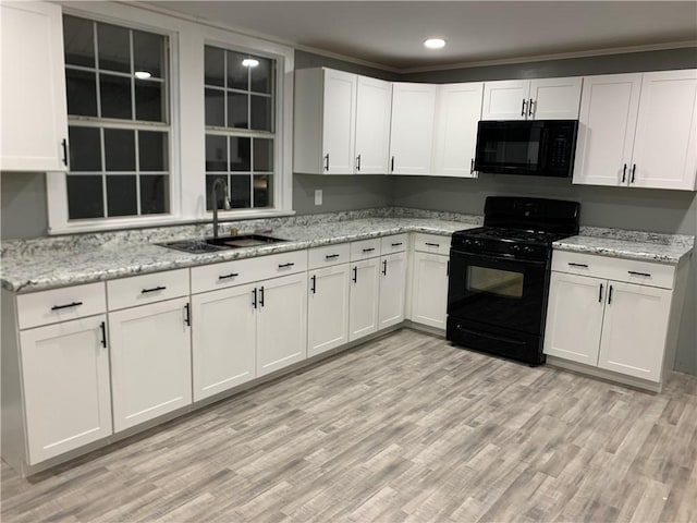 kitchen with sink, light hardwood / wood-style flooring, light stone countertops, black appliances, and white cabinets