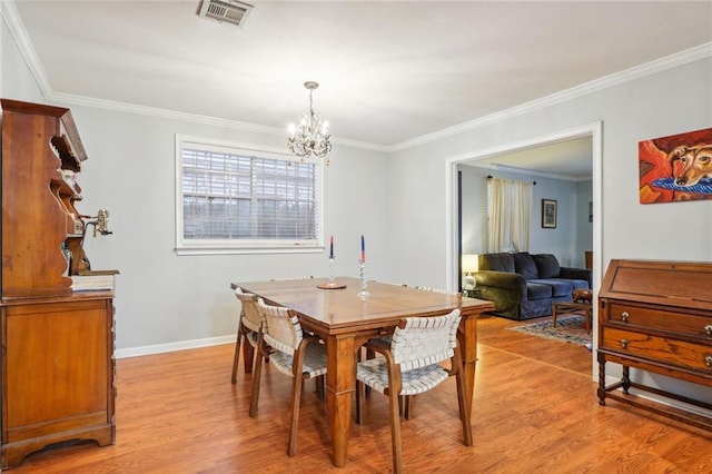 dining room with ornamental molding, a chandelier, and light hardwood / wood-style flooring