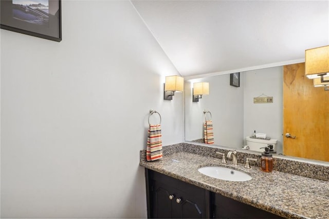 bathroom featuring vanity, vaulted ceiling, and toilet