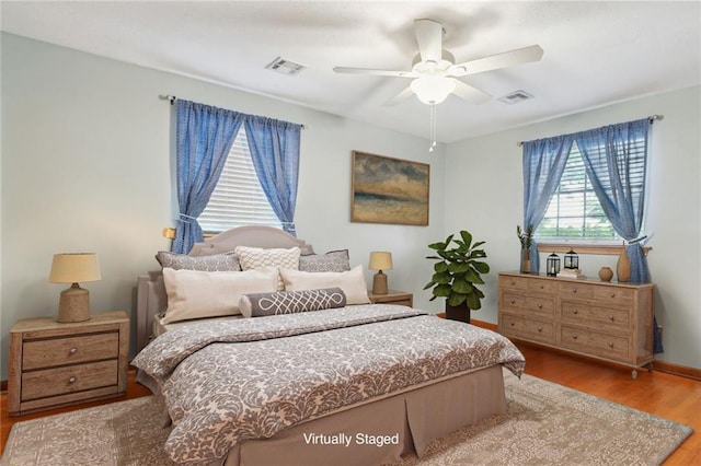 bedroom featuring ceiling fan, wood-type flooring, and multiple windows