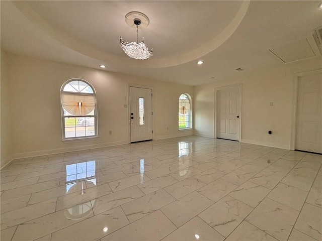 foyer with marble finish floor, baseboards, a raised ceiling, and a wealth of natural light