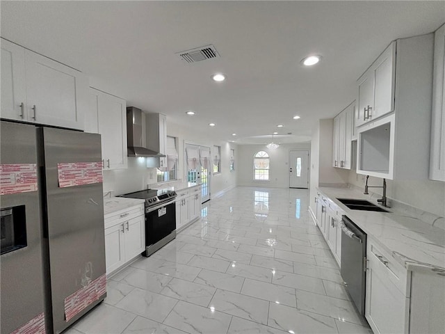 kitchen with marble finish floor, stainless steel appliances, visible vents, a sink, and wall chimney exhaust hood