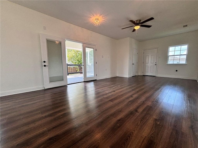 unfurnished living room with baseboards, visible vents, dark wood finished floors, and a wealth of natural light