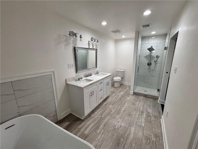 bathroom with wood finished floors, a sink, toilet, and a shower stall