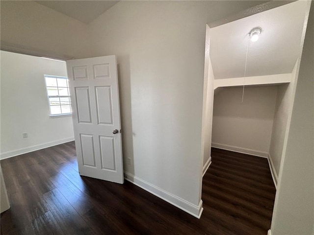 hall featuring dark wood-type flooring, attic access, and baseboards