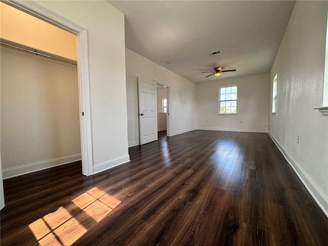 unfurnished bedroom with ceiling fan, dark wood-type flooring, visible vents, and baseboards