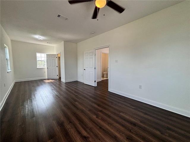 empty room featuring visible vents, dark wood finished floors, baseboards, and ceiling fan