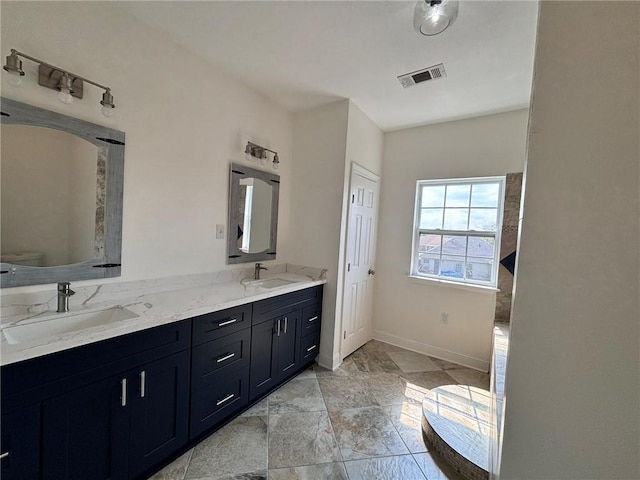 bathroom featuring double vanity, baseboards, toilet, and a sink