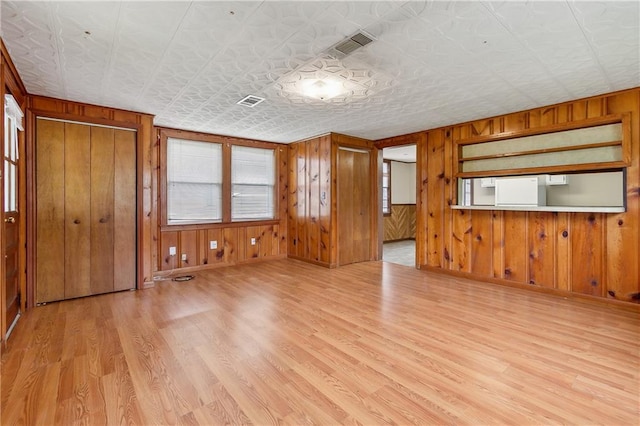 unfurnished living room featuring light hardwood / wood-style flooring and wooden walls