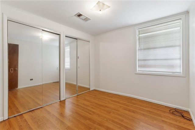 unfurnished bedroom with light wood-type flooring and two closets