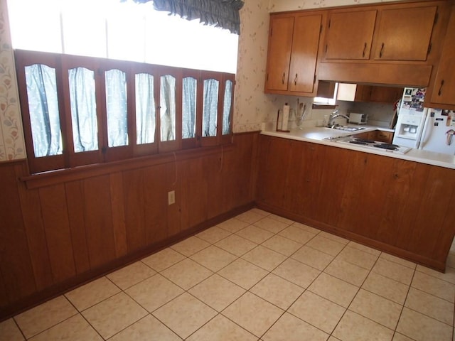 kitchen featuring white gas stovetop, wood walls, and sink