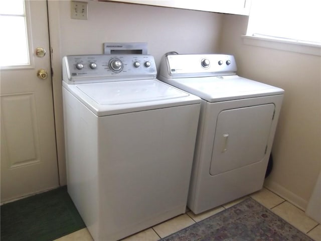 clothes washing area with washing machine and clothes dryer and light tile patterned floors