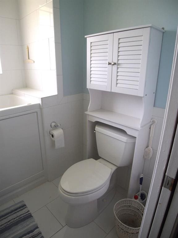 bathroom with tile patterned floors, toilet, and tile walls