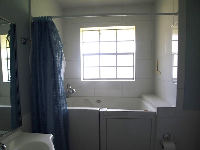 bathroom featuring shower / bath combination with curtain, tile walls, plenty of natural light, and sink