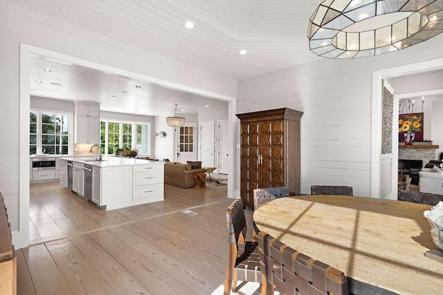 dining space with a fireplace, sink, and light wood-type flooring