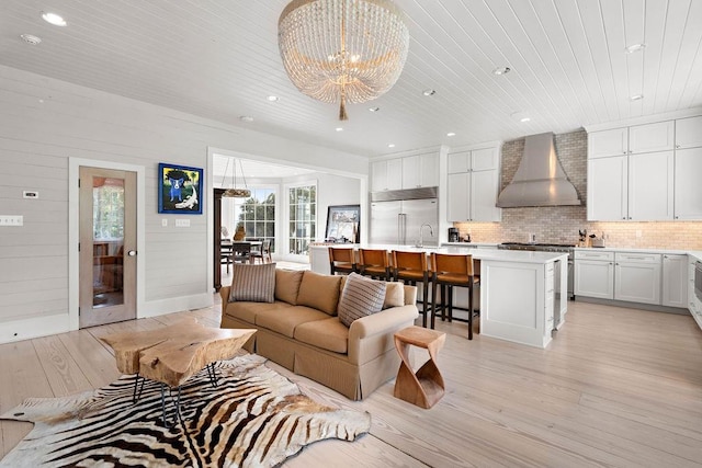 living room with sink, light hardwood / wood-style flooring, and a notable chandelier