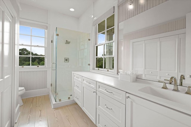 bathroom with a wealth of natural light, wood-type flooring, vanity, and toilet