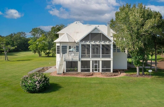 rear view of house featuring a sunroom and a lawn