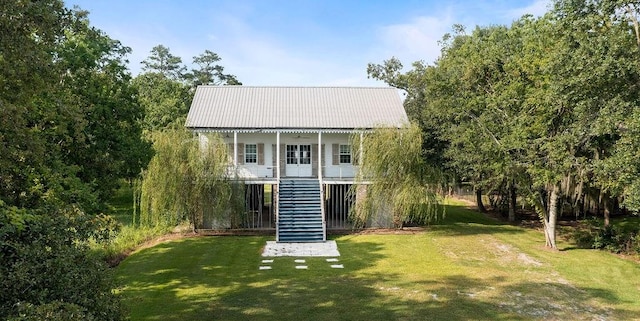 rear view of house featuring a lawn and covered porch