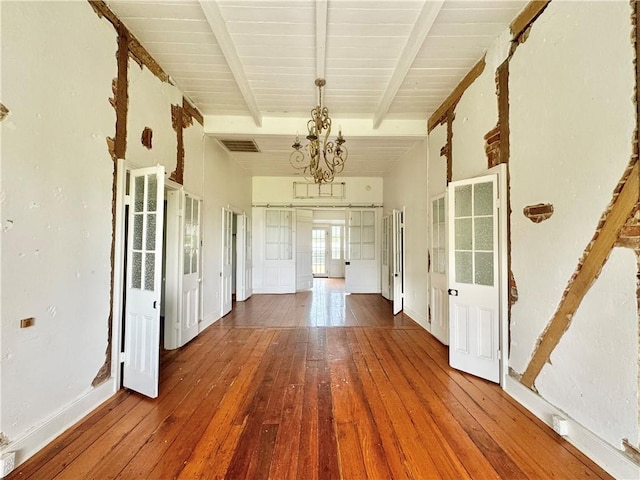 interior space with hardwood / wood-style floors, beam ceiling, and a notable chandelier