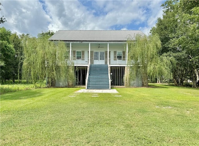 rear view of house featuring ceiling fan and a lawn