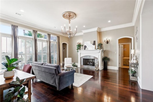 living room with crown molding, dark hardwood / wood-style floors, a notable chandelier, and a fireplace