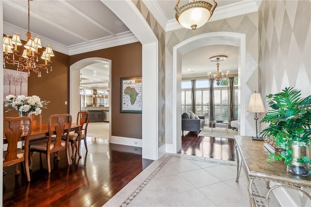 dining space with crown molding, baseboards, a chandelier, wood finished floors, and arched walkways