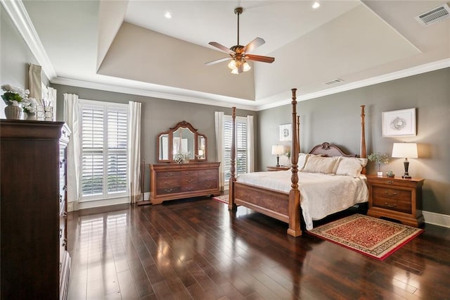 bedroom with visible vents, crown molding, a raised ceiling, and wood finished floors