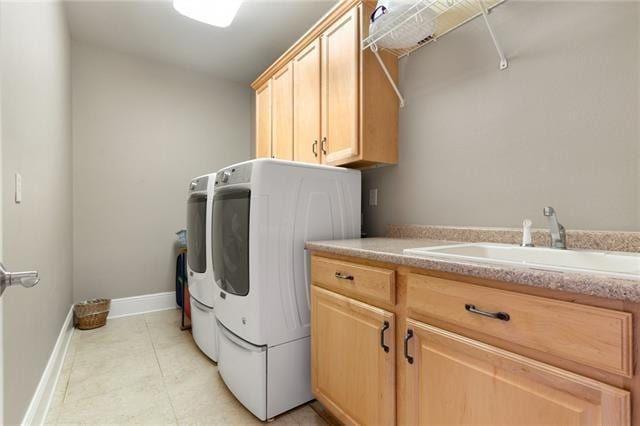 laundry room featuring a sink, washing machine and dryer, cabinet space, light tile patterned flooring, and baseboards