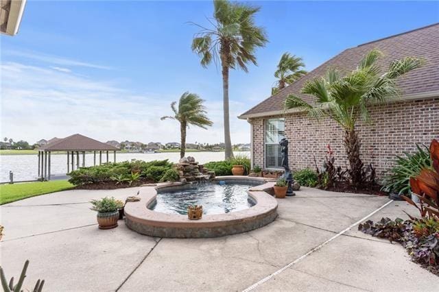 view of patio featuring a gazebo, an in ground hot tub, and a water view