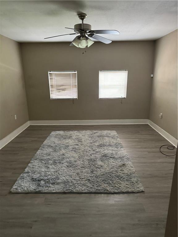 unfurnished room with dark hardwood / wood-style flooring and ceiling fan