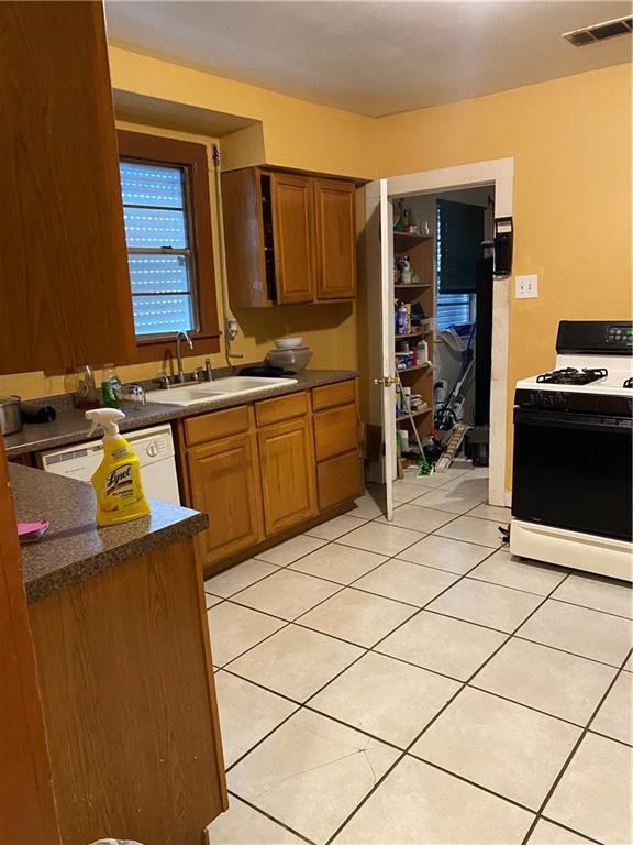 kitchen with light tile patterned floors, sink, dark stone counters, and white appliances