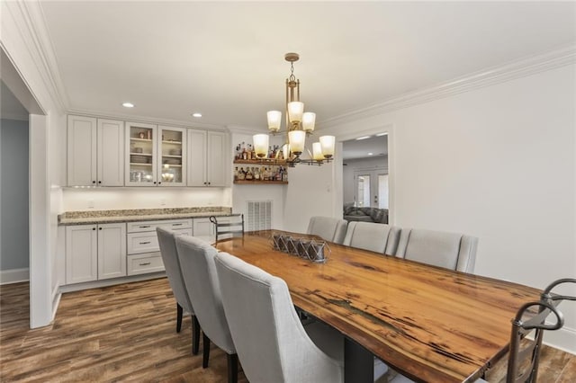 dining space featuring a notable chandelier, dark wood finished floors, crown molding, and recessed lighting