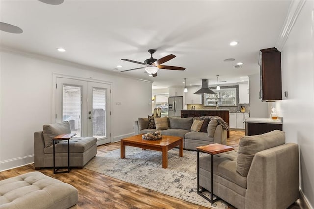 living area featuring ornamental molding, french doors, baseboards, and light wood finished floors