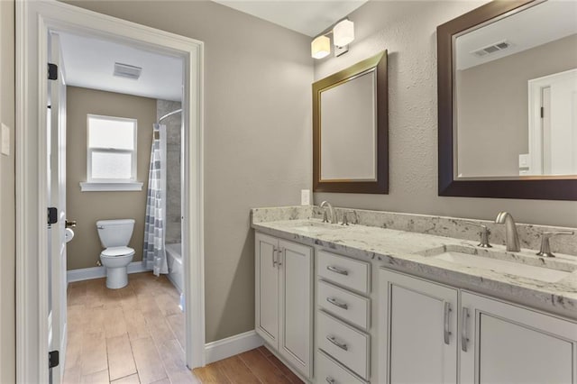 full bathroom featuring toilet, double vanity, a sink, and visible vents