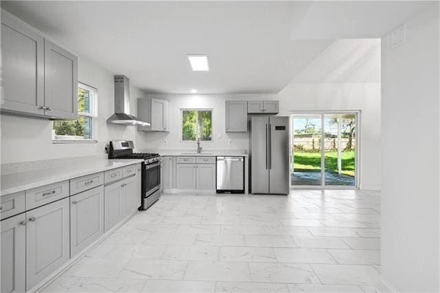 kitchen featuring appliances with stainless steel finishes, light tile patterned flooring, wall chimney range hood, and gray cabinetry