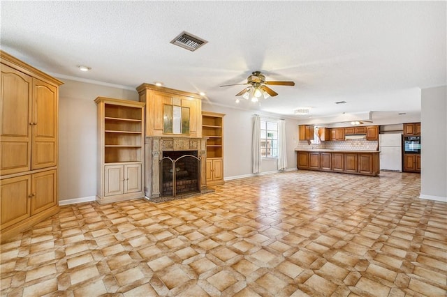 unfurnished living room with ceiling fan, a textured ceiling, crown molding, and light tile patterned floors