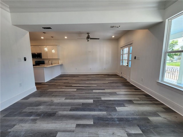 unfurnished living room featuring ceiling fan, sink, dark wood-type flooring, and crown molding