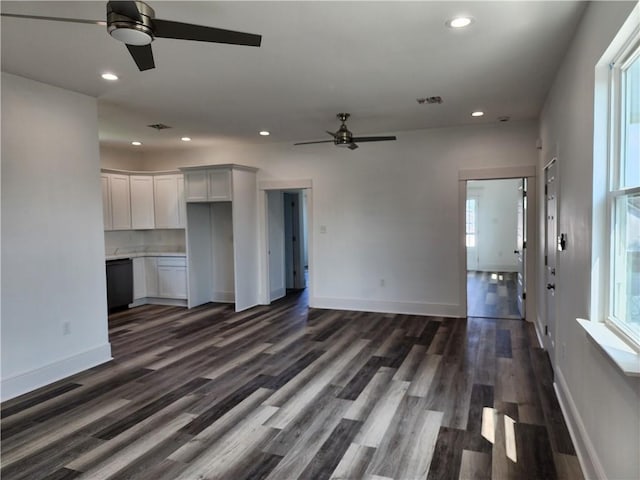 unfurnished living room with a wealth of natural light, ceiling fan, and dark wood-type flooring