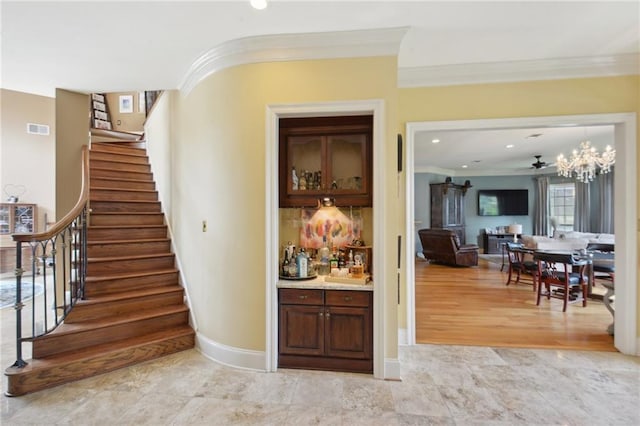 stairway with hardwood / wood-style floors, ceiling fan with notable chandelier, and ornamental molding